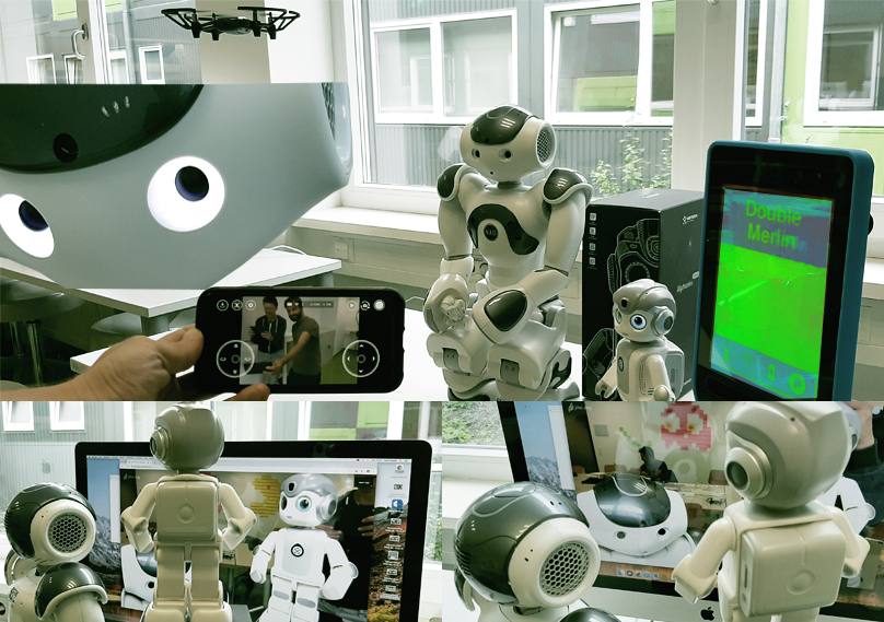 Verschiedene Roboter vor einem Bildschirm. Ein Smartphone fotografiert die Roboter.